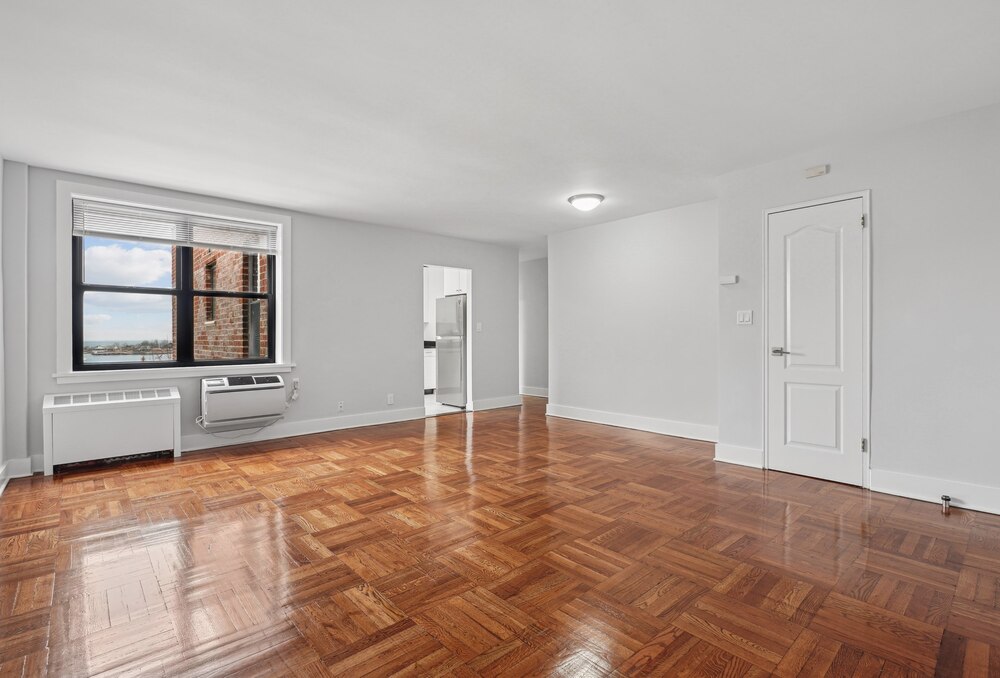 an empty living room with wood flooring and a window